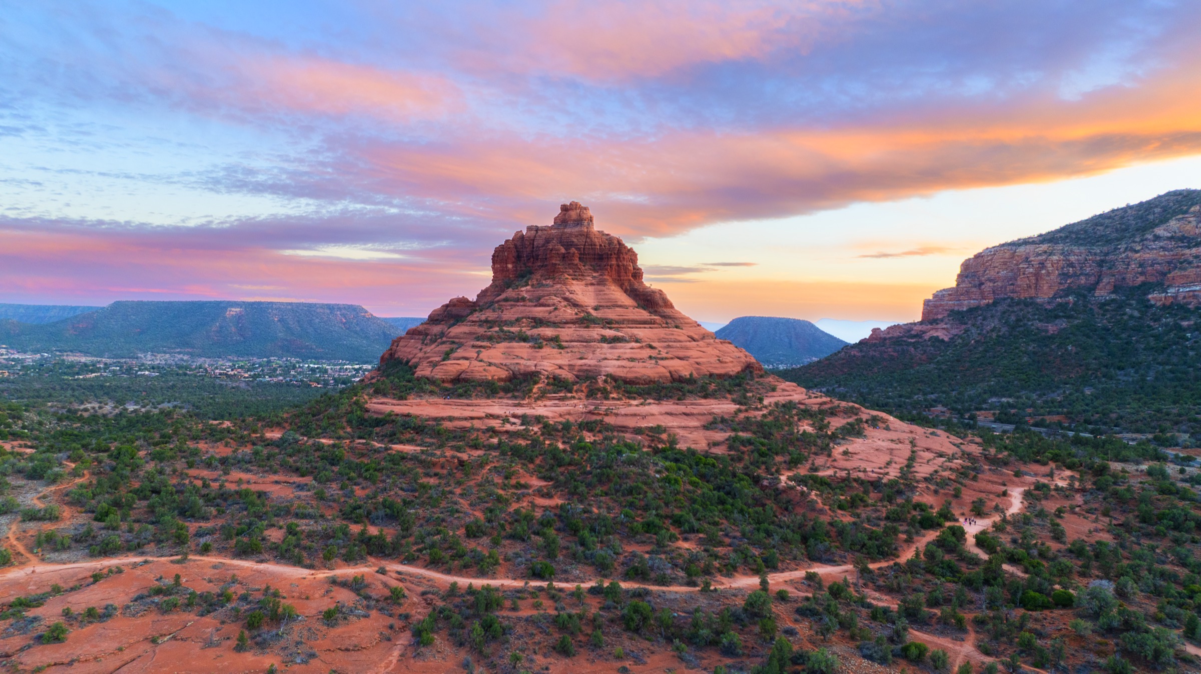 Bell Rock glowing beneath pink sunrise clouds in Sedona, Arizona