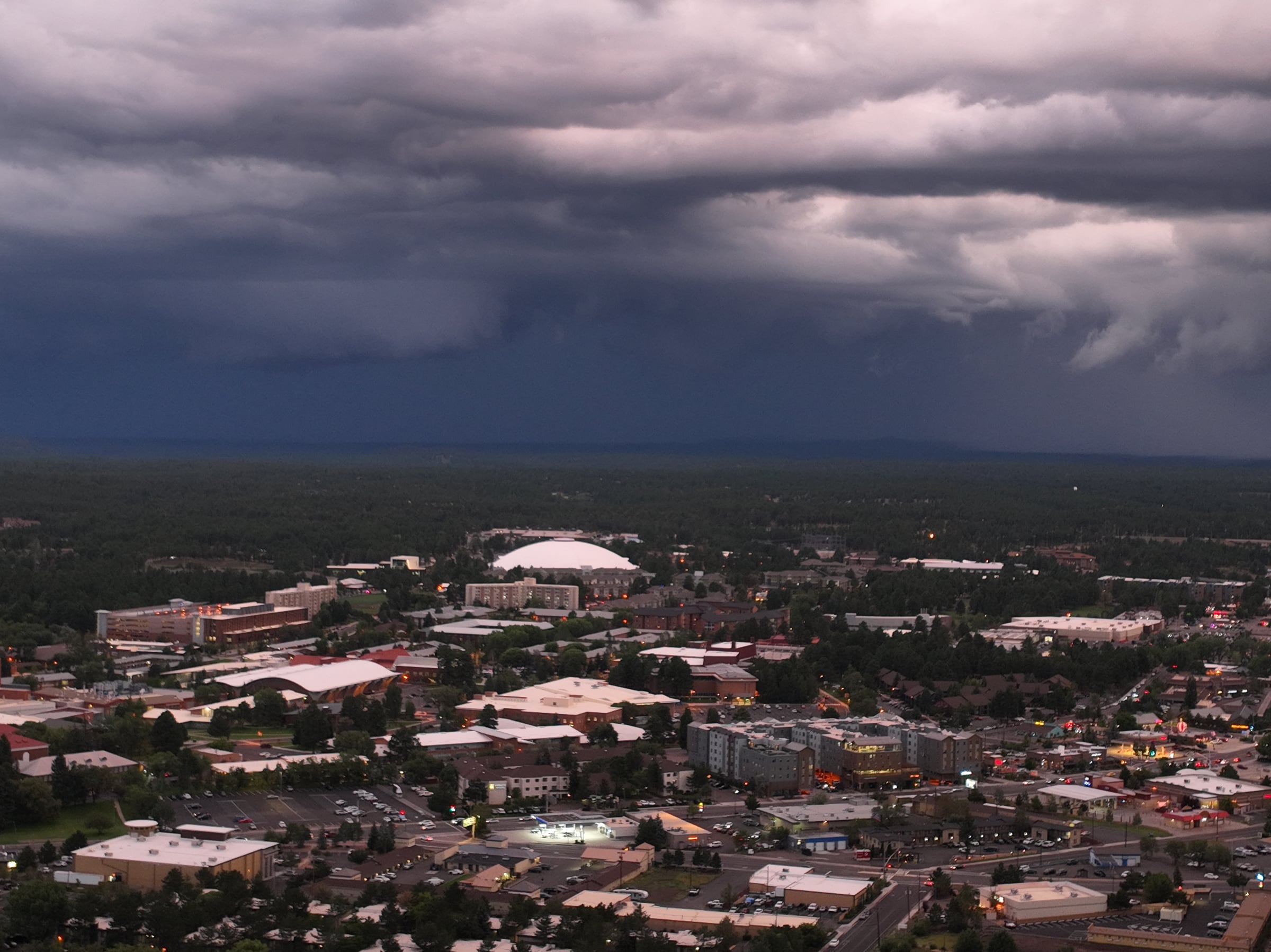 An aerial view of Flagstaff beneath a dramatic summer monsoon sky