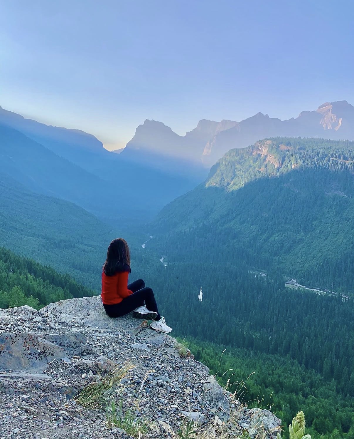 Shannon Roberts sitting above a forested mountain valley at sunrise
